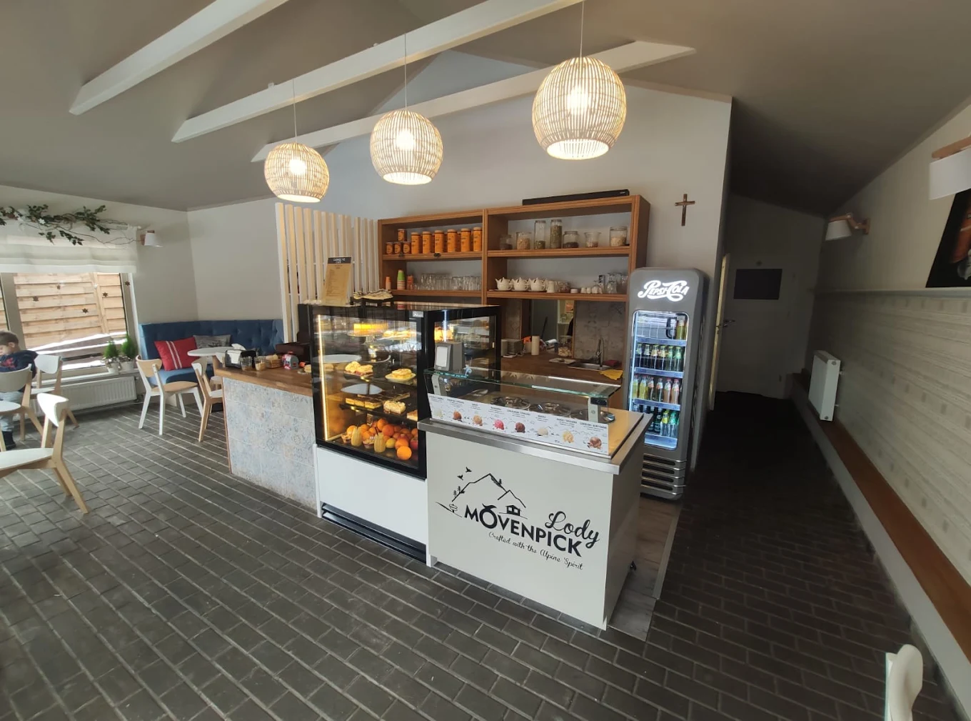 Wnętrze Carmelove Cafe — lada z witryną i lampy nad barem